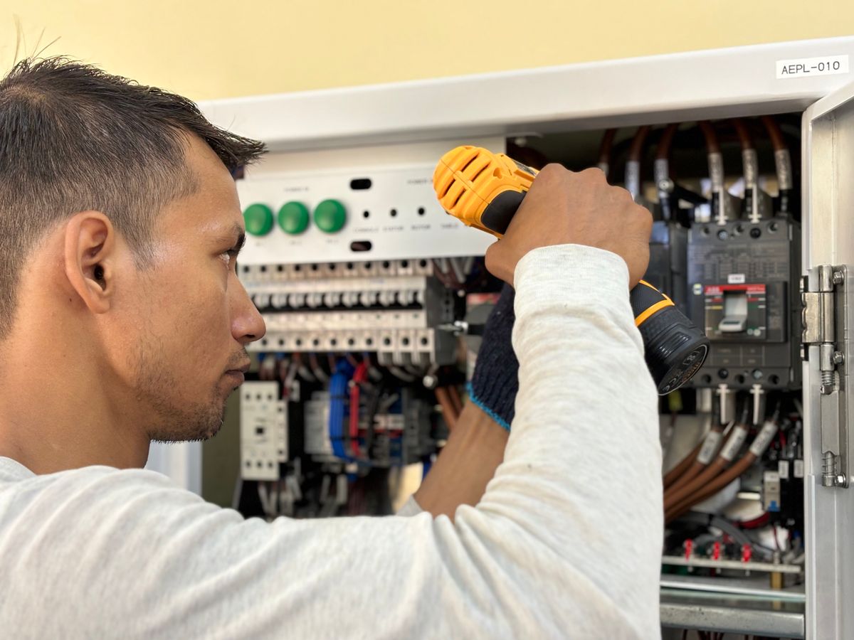 An electrician working safely at a service panel